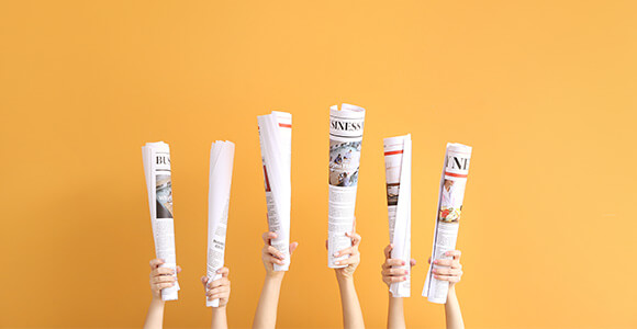 Hände halten Zeitungen hoch - Symbolbild für Presseartikel