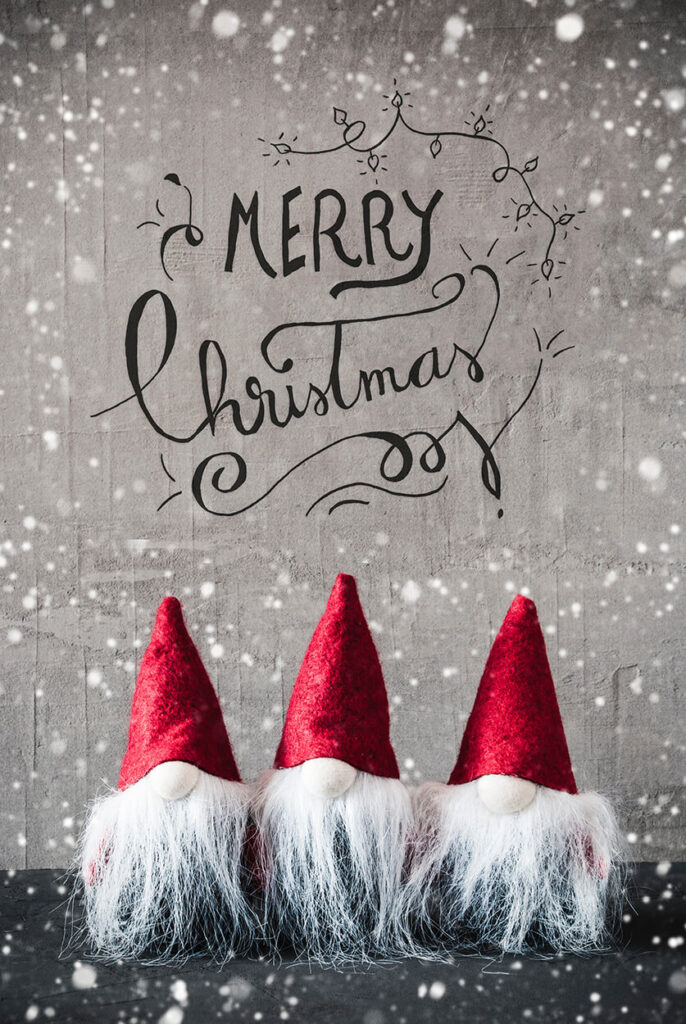 Three christmas elves in front of a grey background with the text "Merry Christmas" above their heads.